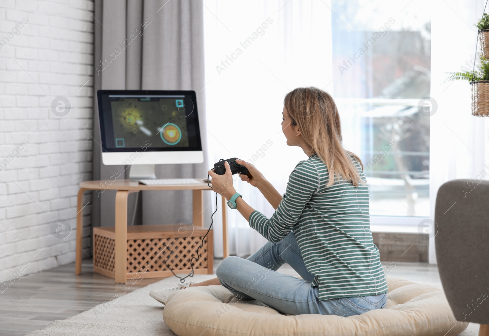 Photo of Young woman playing video game at home