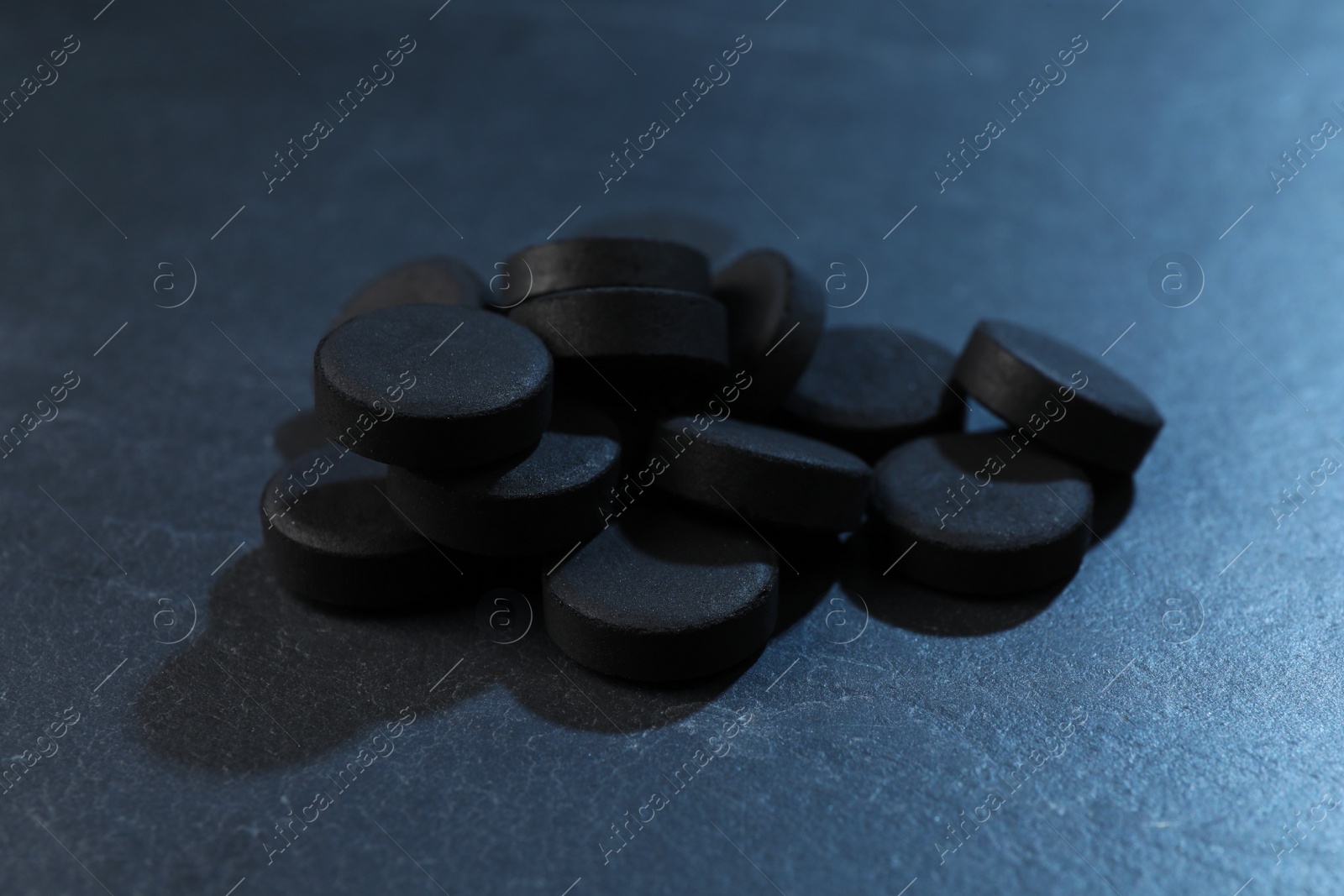 Photo of Pile of activated charcoal pills on table, closeup. Potent sorbent