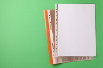 File folder with punched pockets on green background, top view. Space for text