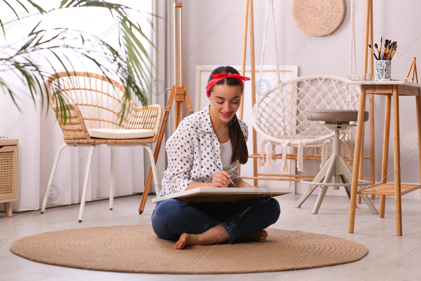 Photo of Happy woman artist drawing picture on canvas in studio