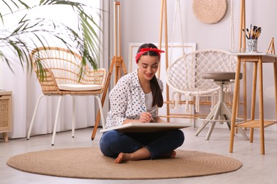 Photo of Happy woman artist drawing picture on canvas in studio