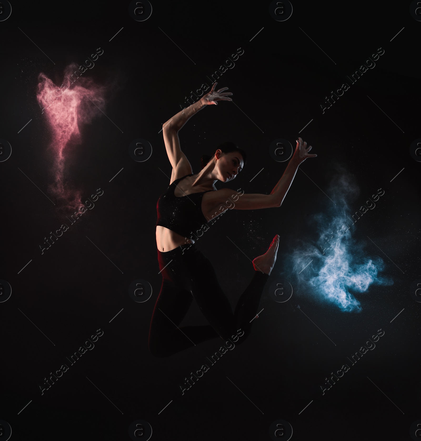 Photo of Professional acrobat with chalk powder exercising in dark studio