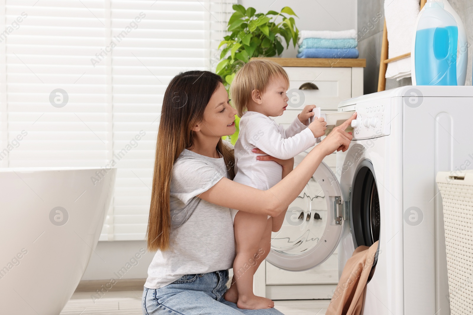 Photo of Mother with her daughter washing baby clothes in bathroom