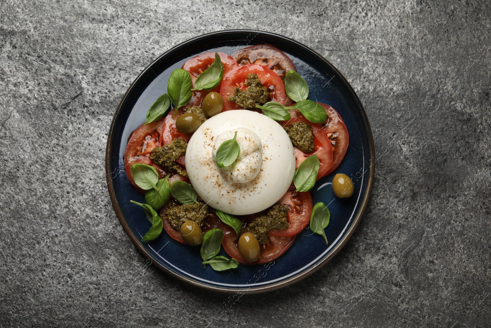 Photo of Delicious burrata salad on grey table, top view