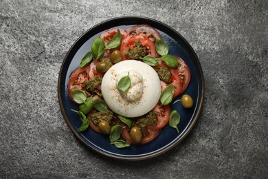 Photo of Delicious burrata salad on grey table, top view