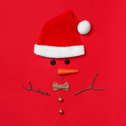 Photo of Funny snowman made with different elements on red background, flat lay