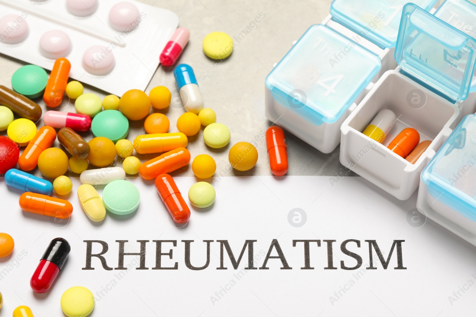 Photo of Paper with word Rheumatism and pills on light gray table