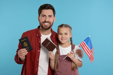 Immigration. Happy man with his daughter holding passports and American flag on light blue background