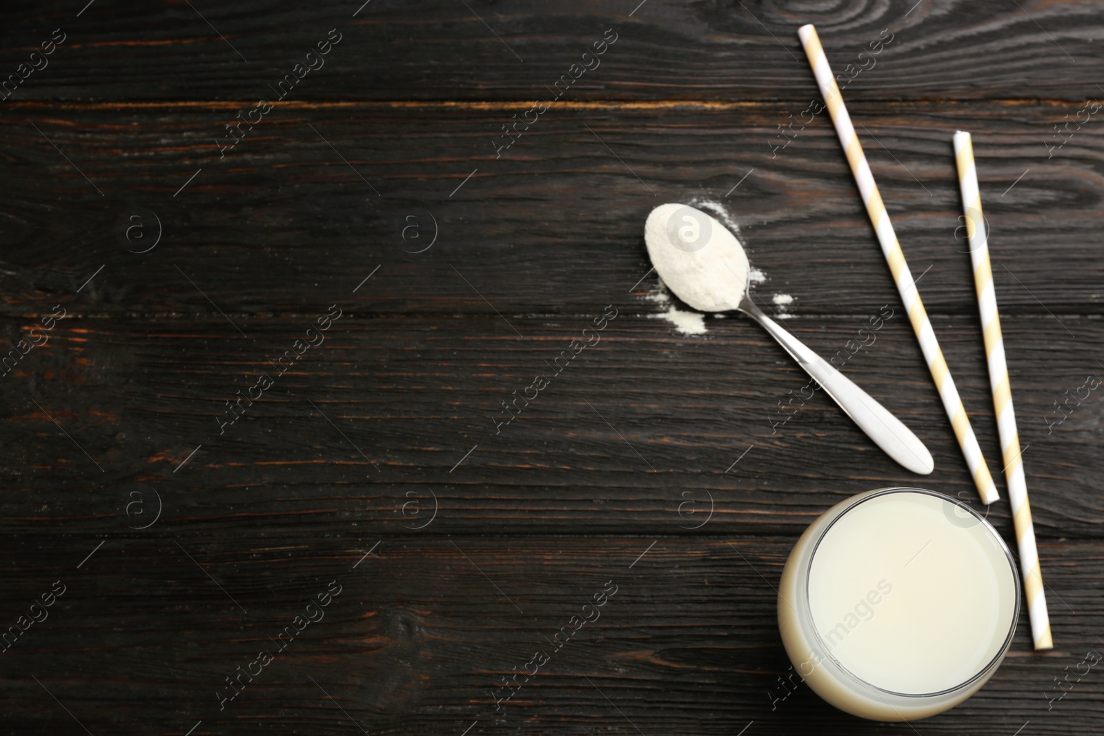 Photo of Protein shake, powder and straws on black wooden table, flat lay. Space for text