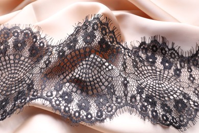 Beautiful black lace on beige fabric, top view