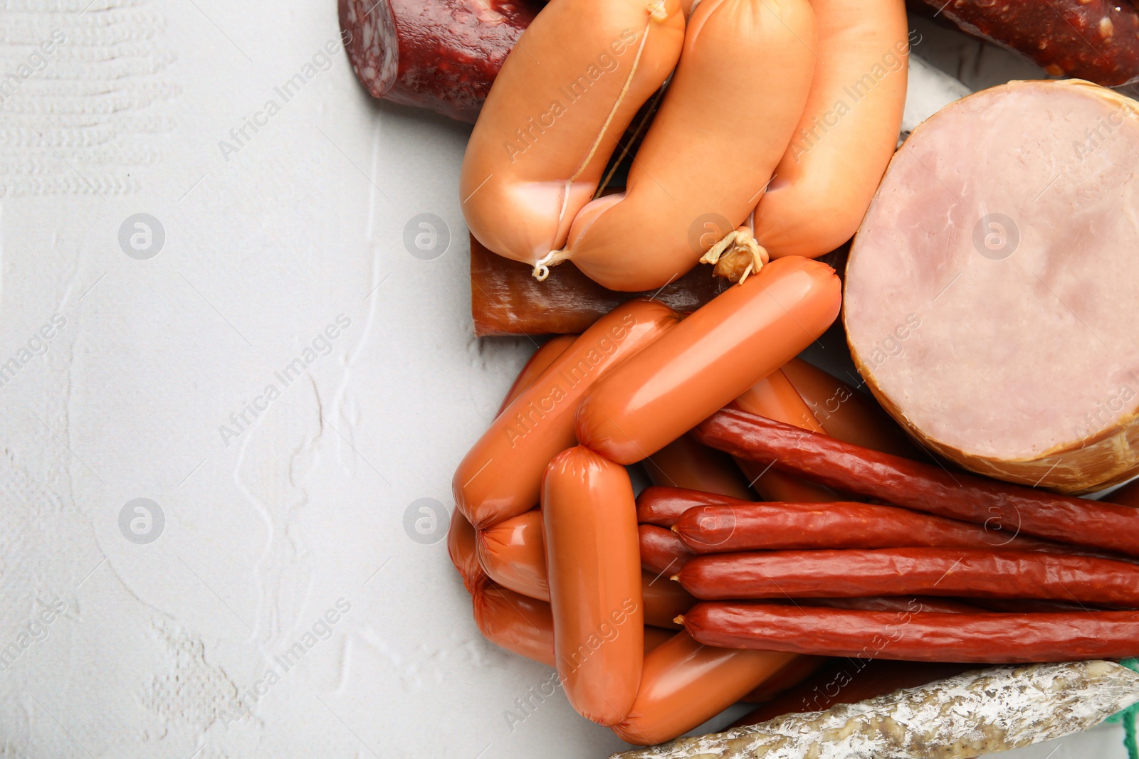 Photo of Different types of sausages on white textured table, above view with space for text