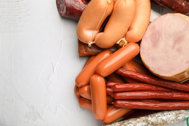 Different types of sausages on white textured table, above view with space for text