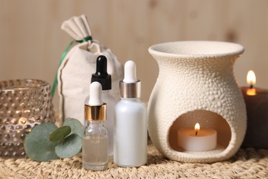 Photo of Different aromatherapy products, burning candles and eucalyptus leaves on table, closeup