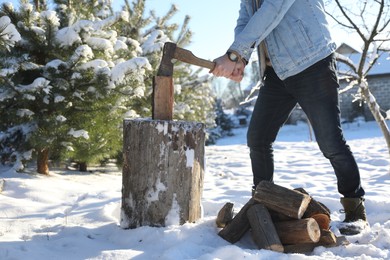 Man chopping wood with axe outdoors on winter day, closeup