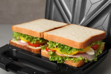 Photo of Modern grill maker with tasty sandwiches, closeup view