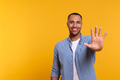 Photo of Man giving high five on yellow background. Space for text