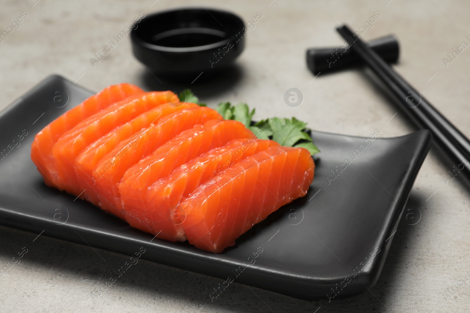 Photo of Plate of tasty salmon slices and parsley on grey table, closeup. Delicious sashimi dish