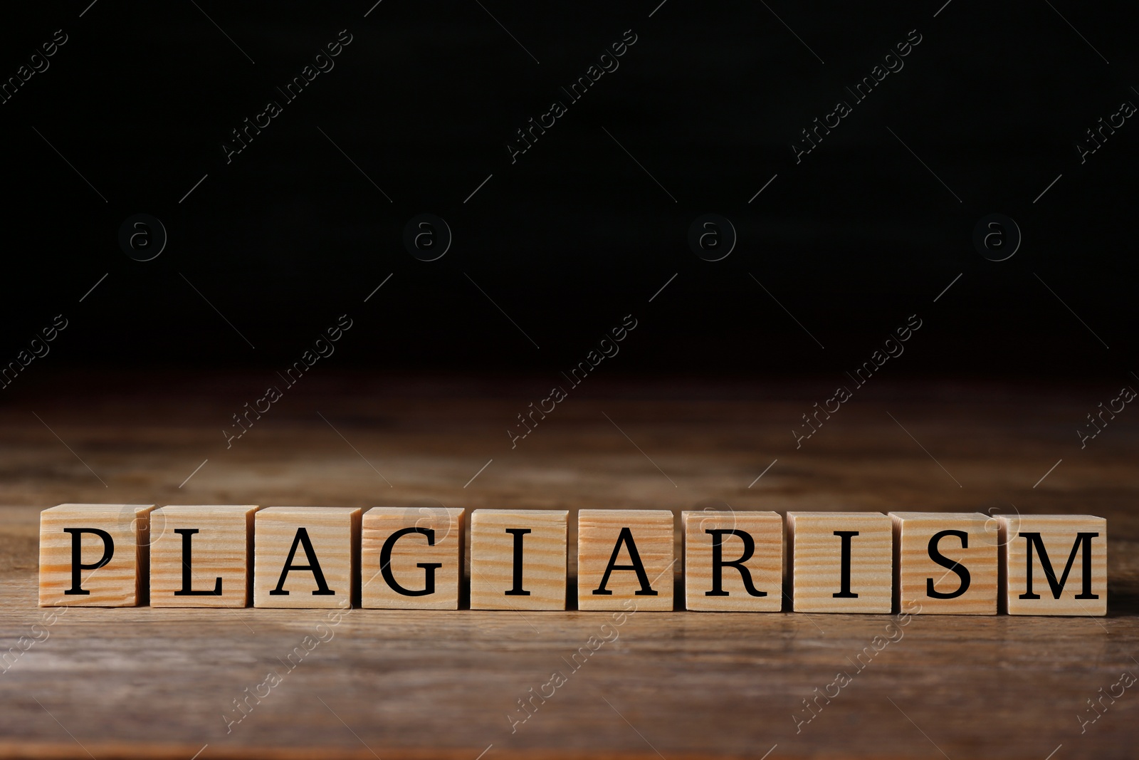 Photo of Wooden cubes with word Plagiarism on table, space for text