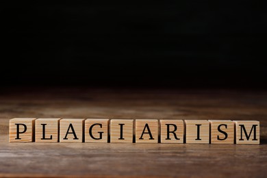 Wooden cubes with word Plagiarism on table, space for text