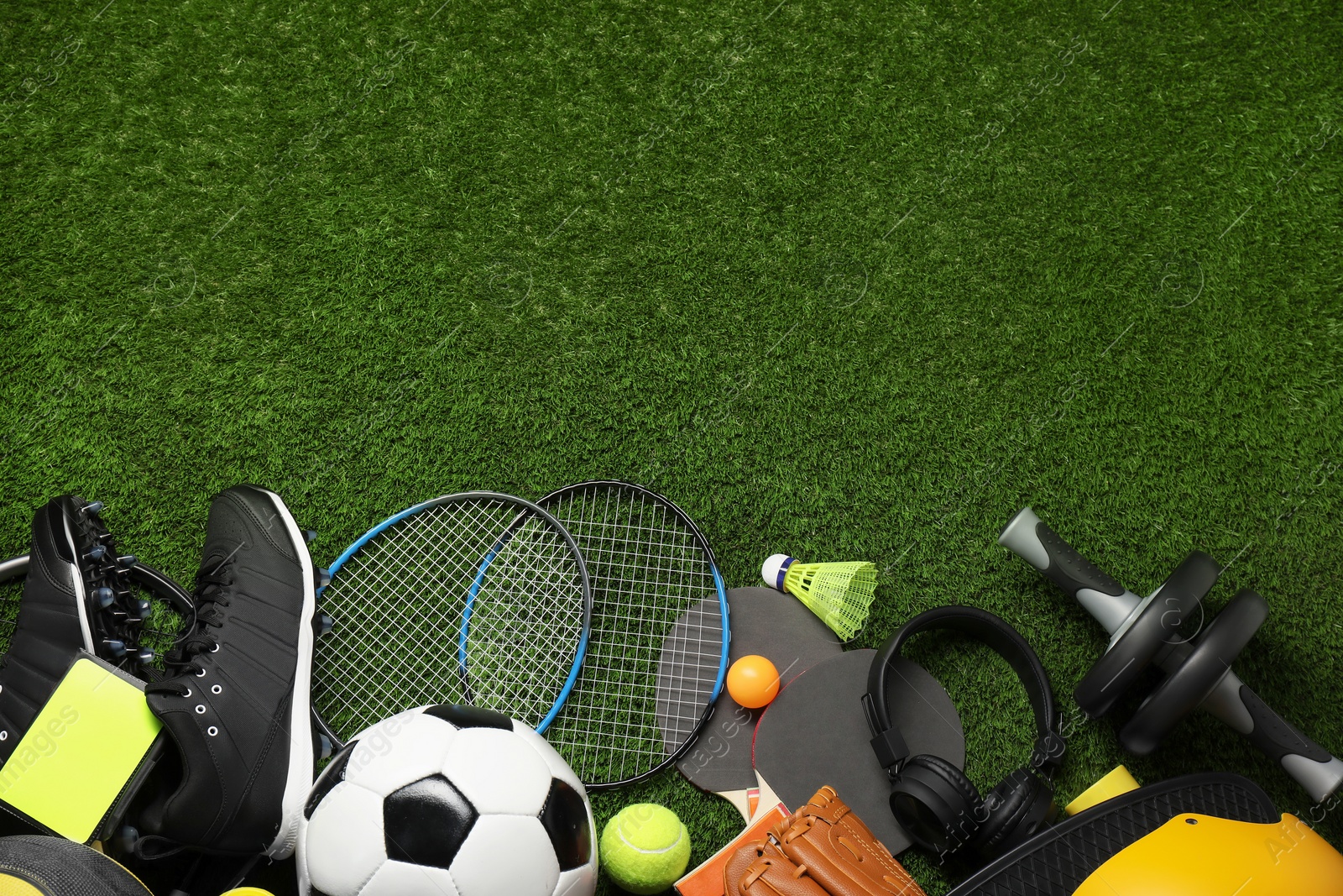 Photo of Different sports equipment on green grass, flat lay. Space for text