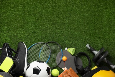 Photo of Different sports equipment on green grass, flat lay. Space for text