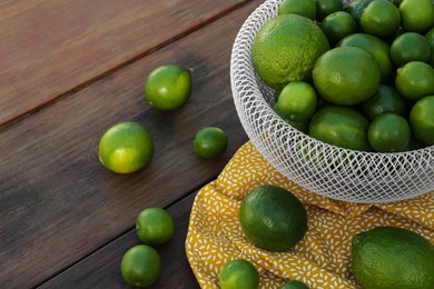 Photo of Fresh ripe limes on wooden table, space for text