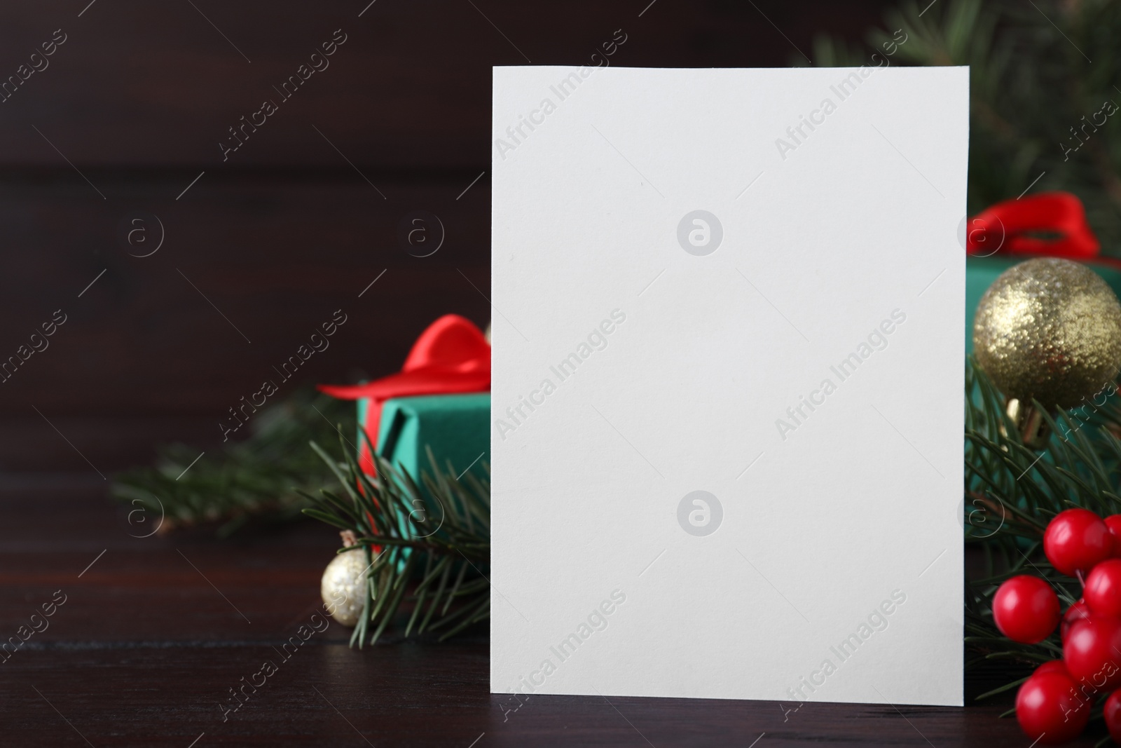 Photo of Blank greeting card near Christmas decorations on wooden table, closeup. Space for text