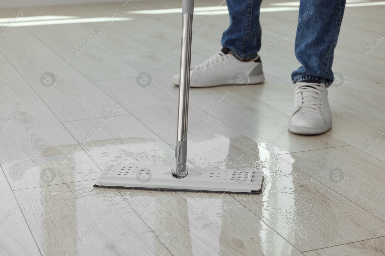 Photo of Man cleaning floor with mop indoors, closeup