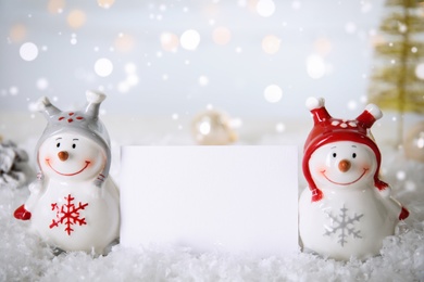 Photo of Decorative snowmen near blank card on artificial snow, space for text
