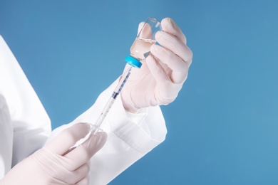 Photo of Doctor with syringe and medicine for vaccination on color background