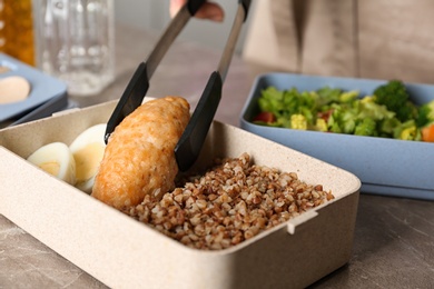 Woman preparing food for her child at table in kitchen, closeup. Healthy school lunch