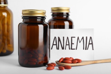 Photo of Card with word Anaemia and pills on light background