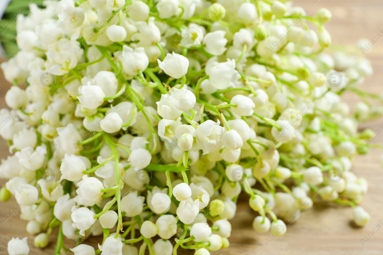 Photo of Beautiful lily of the valley bouquet on wooden table, closeup