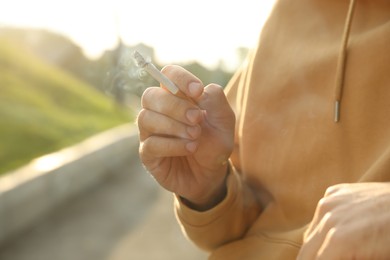 Photo of Man with cigarette outdoors, closeup of hand