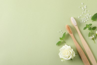Photo of Flat lay composition with toothbrushes and herbs on light olive background. Space for text