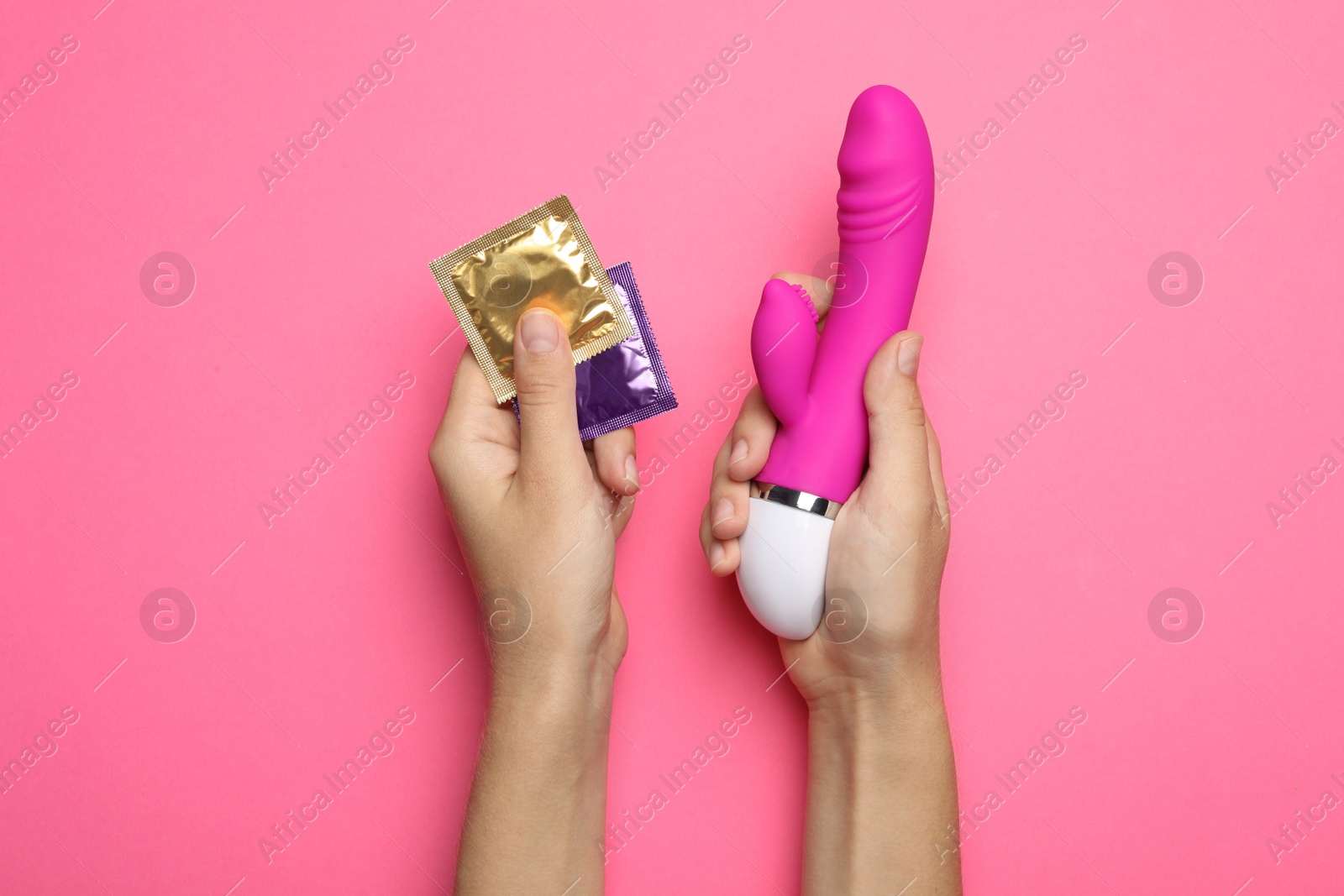 Photo of Woman with vibrator and condoms on pink background, top view. Sex game