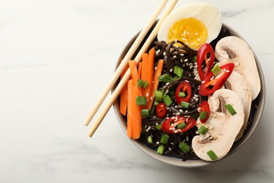 Photo of Tasty buckwheat noodles (soba) with chili pepper, egg, carrot, mushrooms and chopsticks on white marble table, top view. Space for text