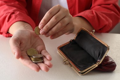 Poor woman counting coins at white table, closeup