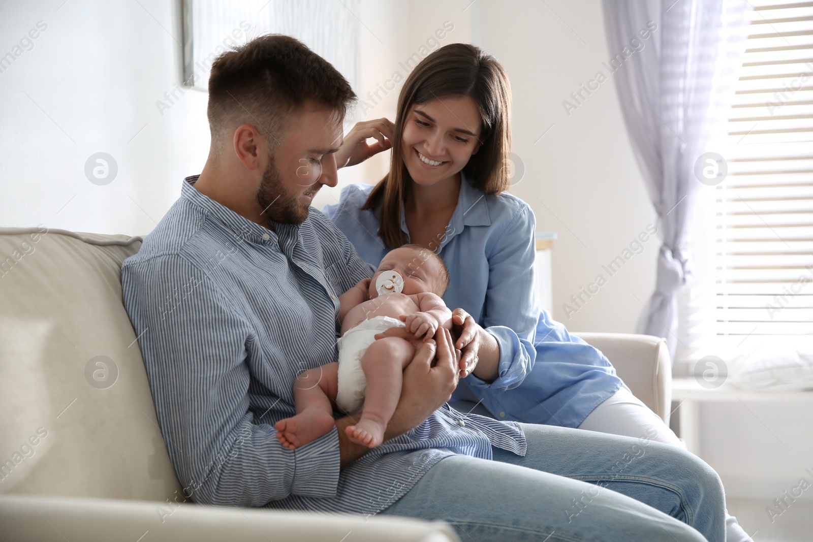 Photo of Happy couple with their newborn baby at home