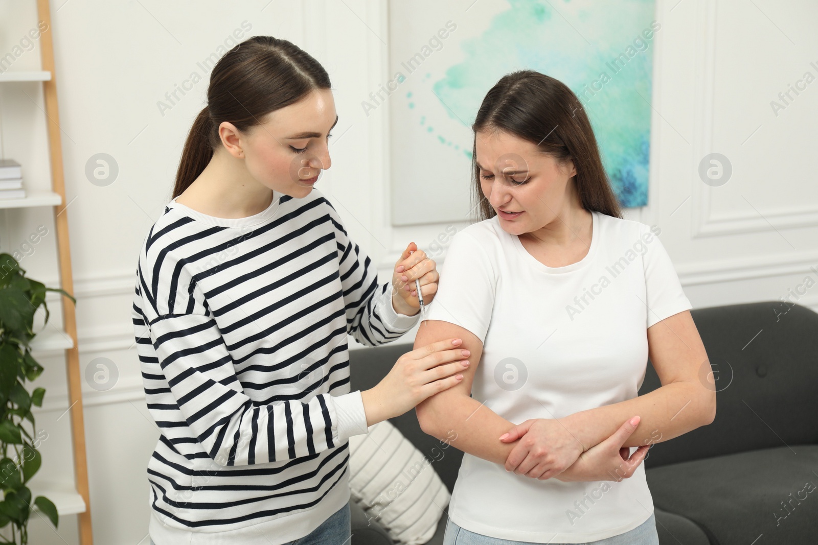 Photo of Woman giving insulin injection to her diabetic friend at home