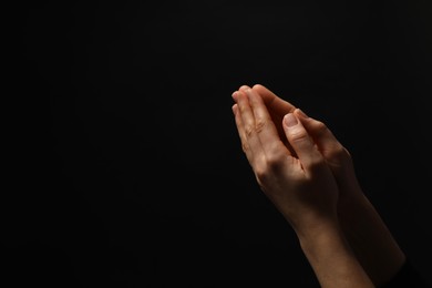 Photo of Religion. Christian woman praying on black background, closeup. Space for text