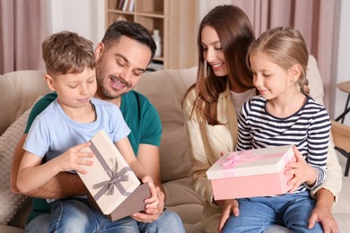 Happy family presenting each other with gifts on sofa at home