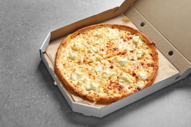 Photo of Carton box with delicious pizza on grey background