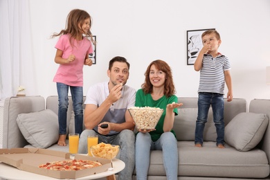 Family watching TV with popcorn in room