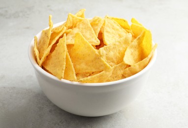 Bowl with tasty tortilla chips (nachos) on grey table