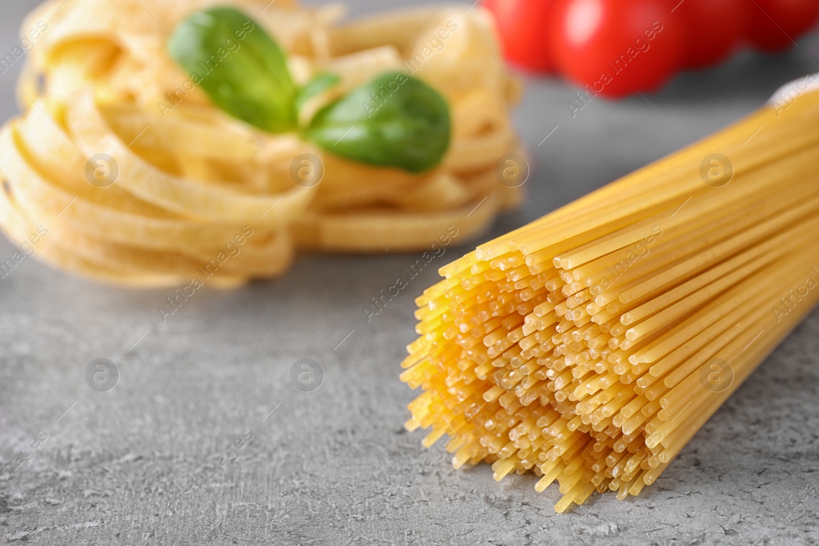 Photo of Uncooked spaghetti on grey table, space for text. Italian pasta