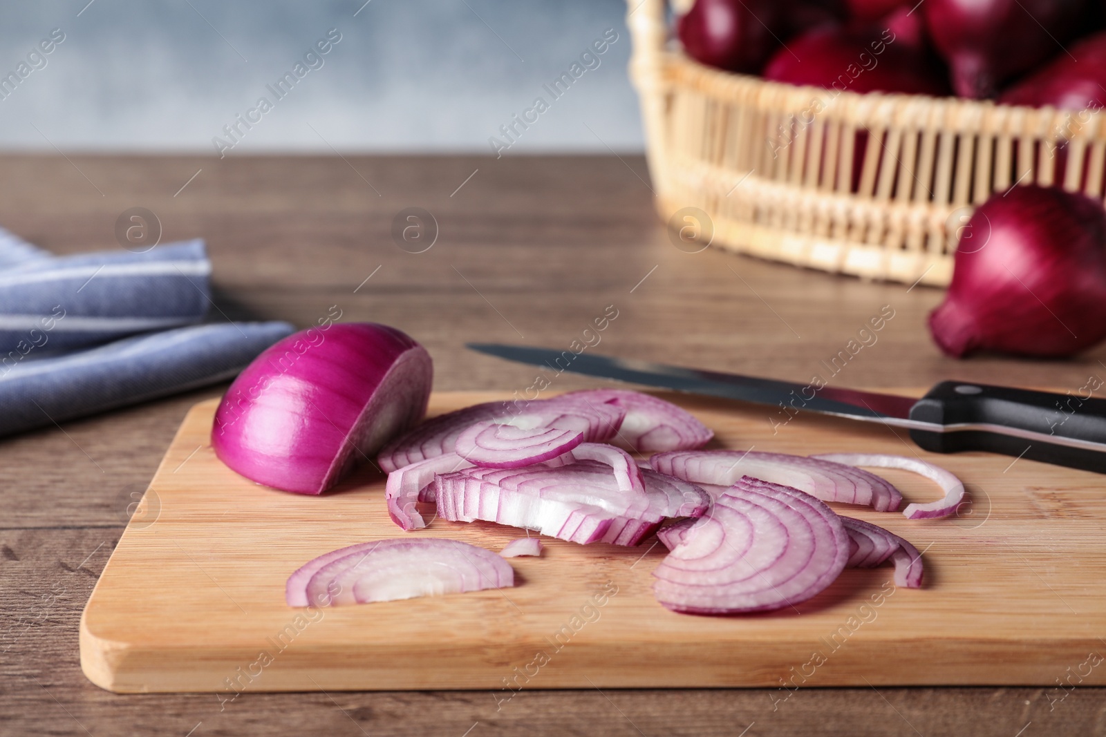 Photo of Wooden board with cut fresh red onion on table