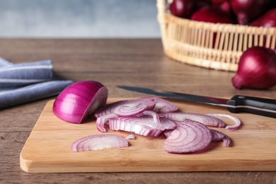 Photo of Wooden board with cut fresh red onion on table