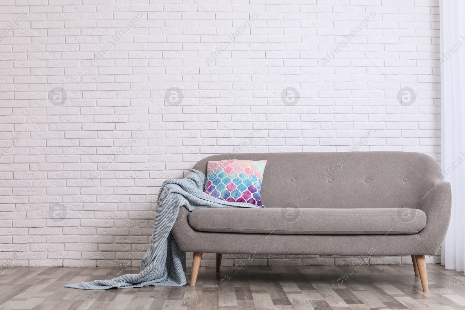 Photo of Minimalist living room interior with cozy sofa, pillow and plaid near brick wall. Space for text