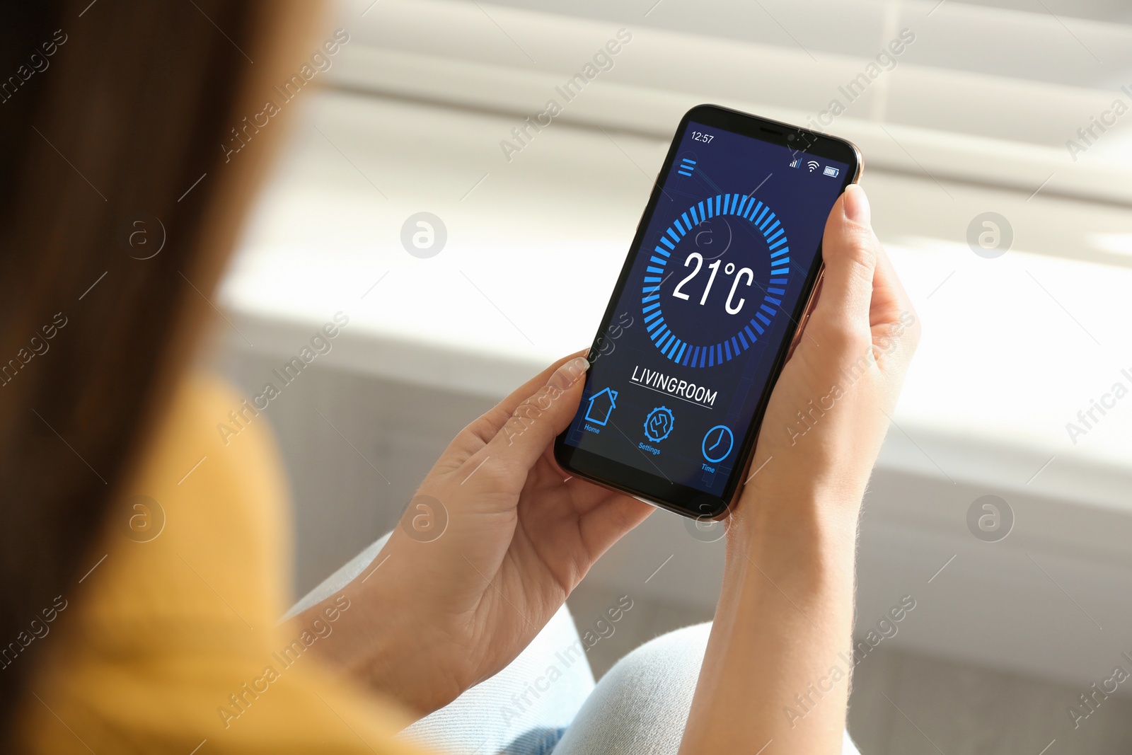 Image of Woman using smartphone to control heating system in house, closeup